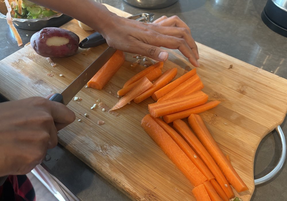 Carrots being sliced into sticks on a cutting board