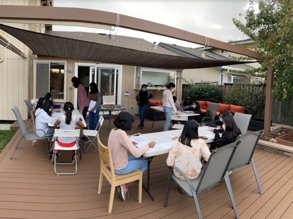 A wide view of the patio workshop with students drawing at several tables