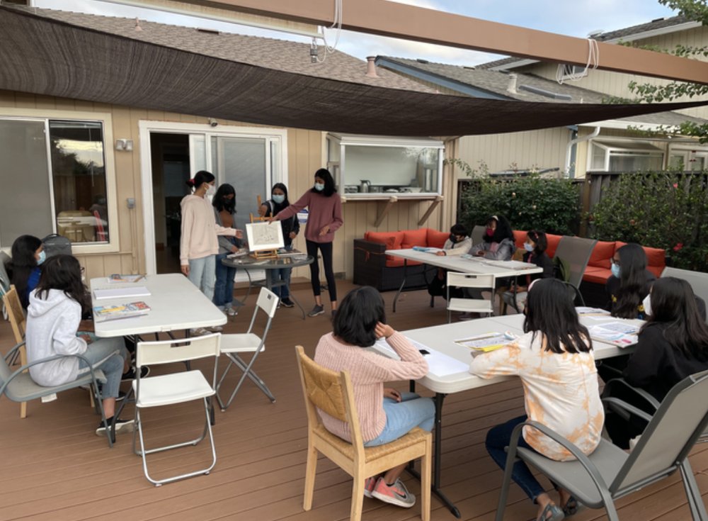 A CARES member showing the sample drawing to students seated at tables