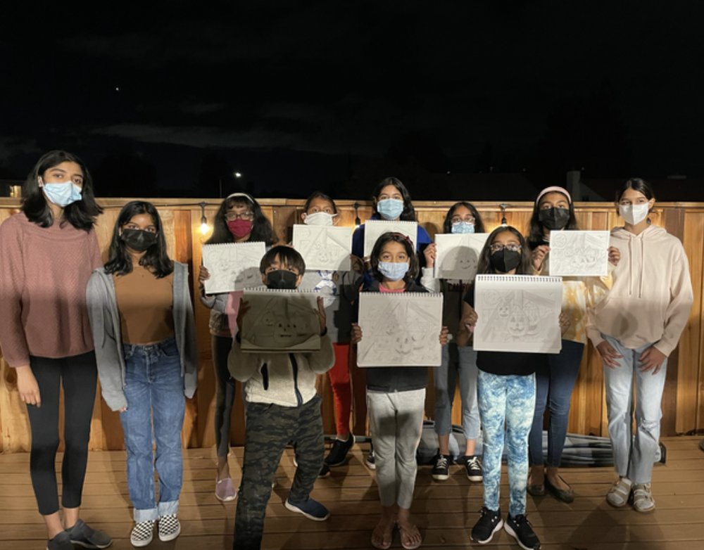 Students holding up their finished pencil sketches of pumpkins