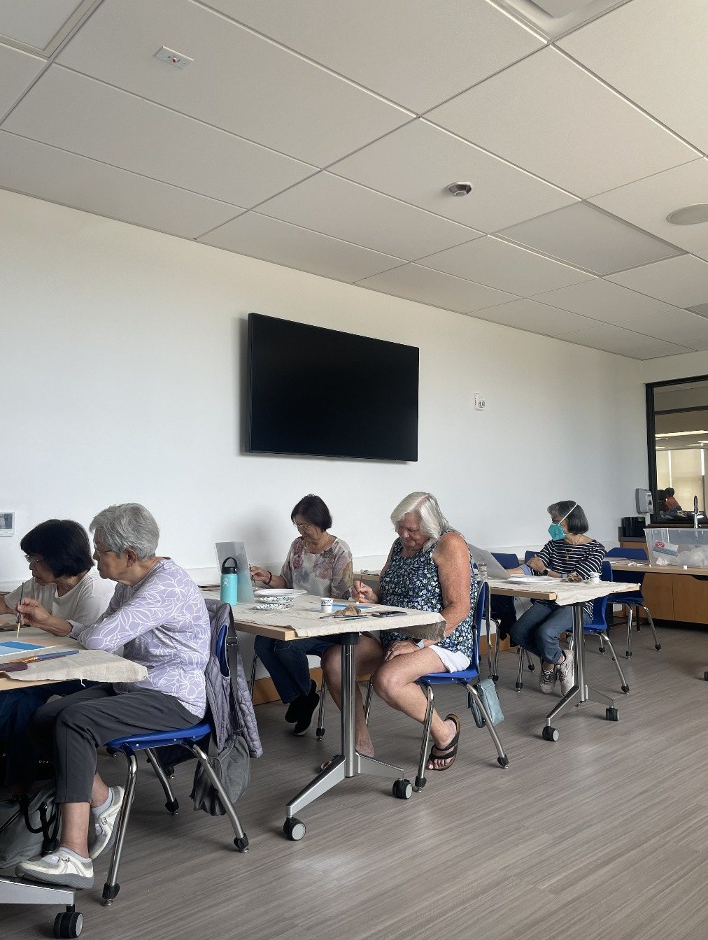 Participants painting at tables in a bright, spacious room