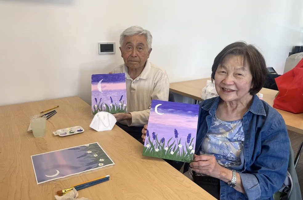 A man and a woman holding up their lavender moon paintings