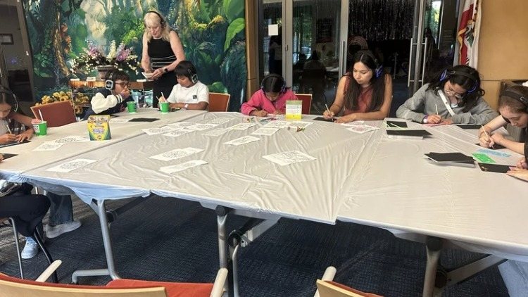 Guests of all ages sitting around a long table coloring and drawing