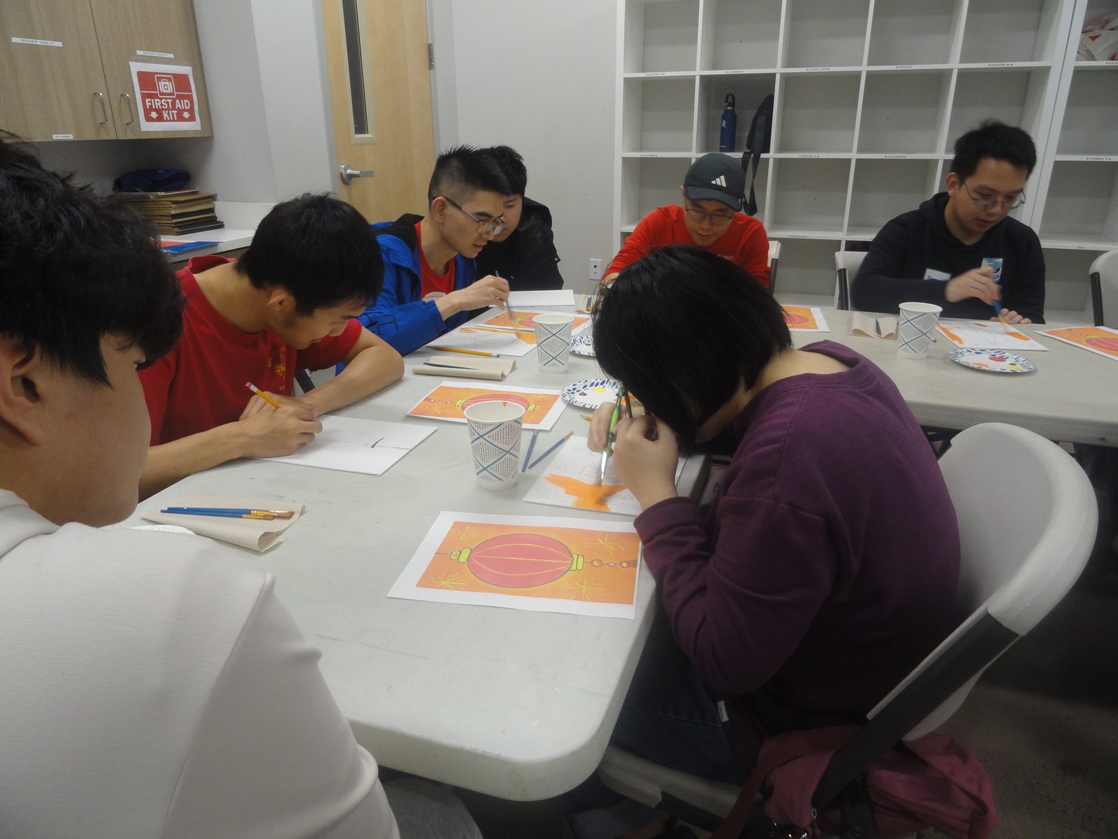 Participants and volunteers painting at long tables