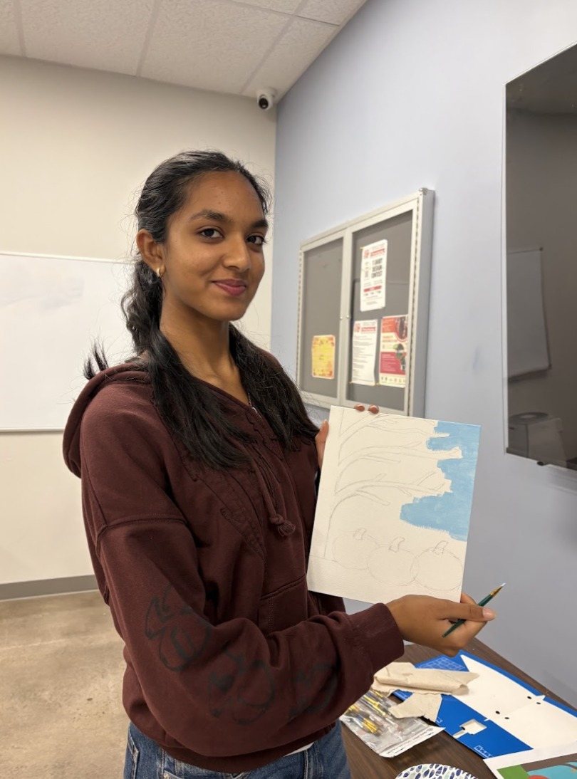 A CARES officer holding up her pencil sketch and first coat of blue sky