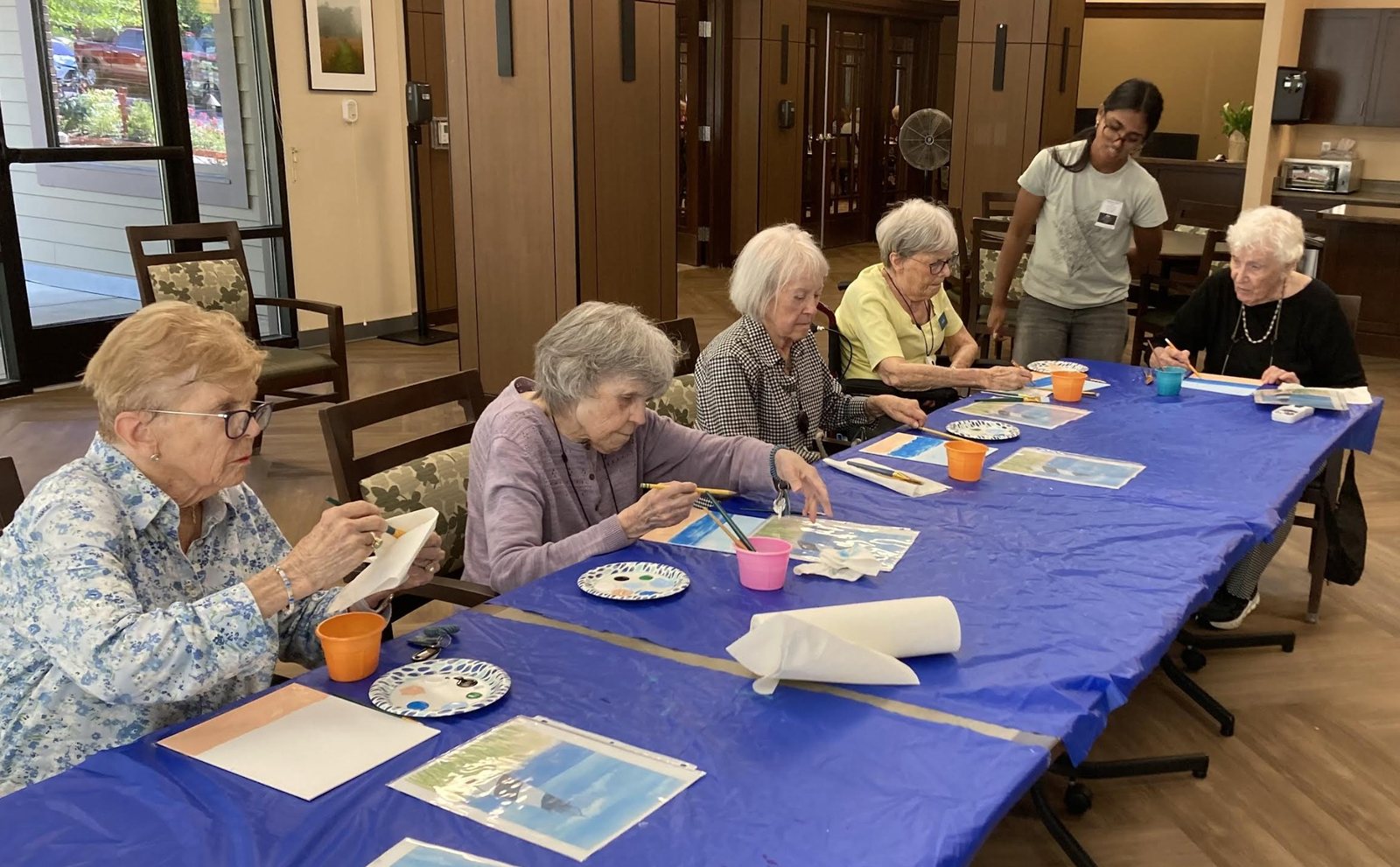 Residents painting along a long table while CARES officers help