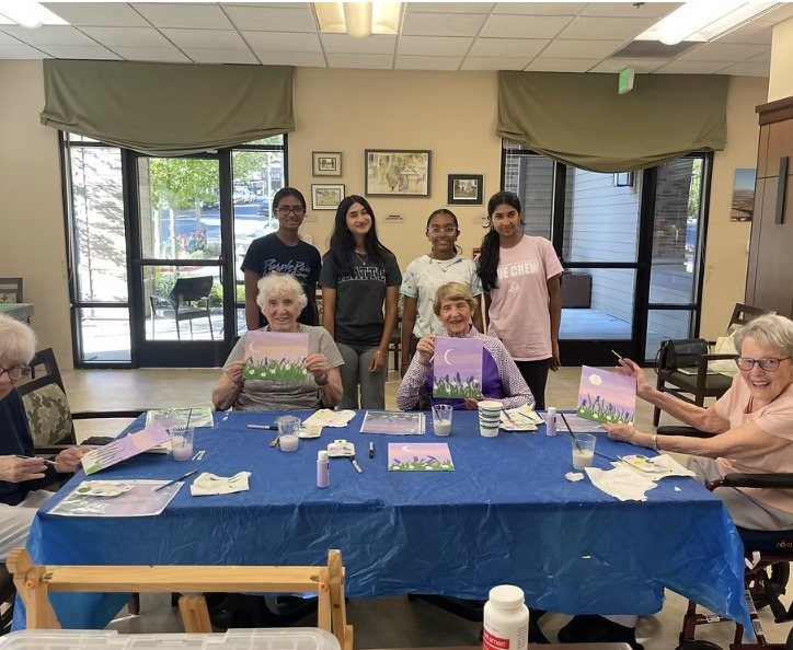 CARES officers standing behind residents who hold up their lavender moon paintings