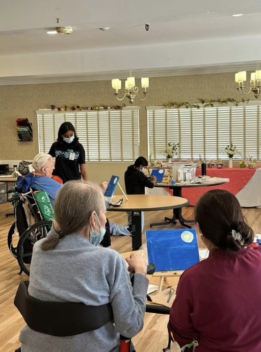 Residents painting at a round table with a CARES officer