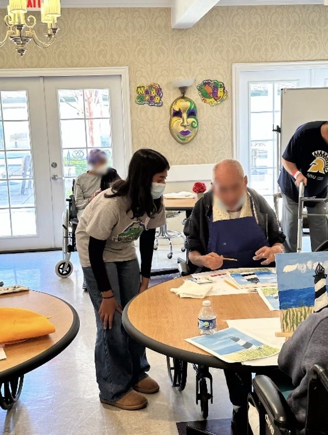A CARES officer helping a resident painting at a round table