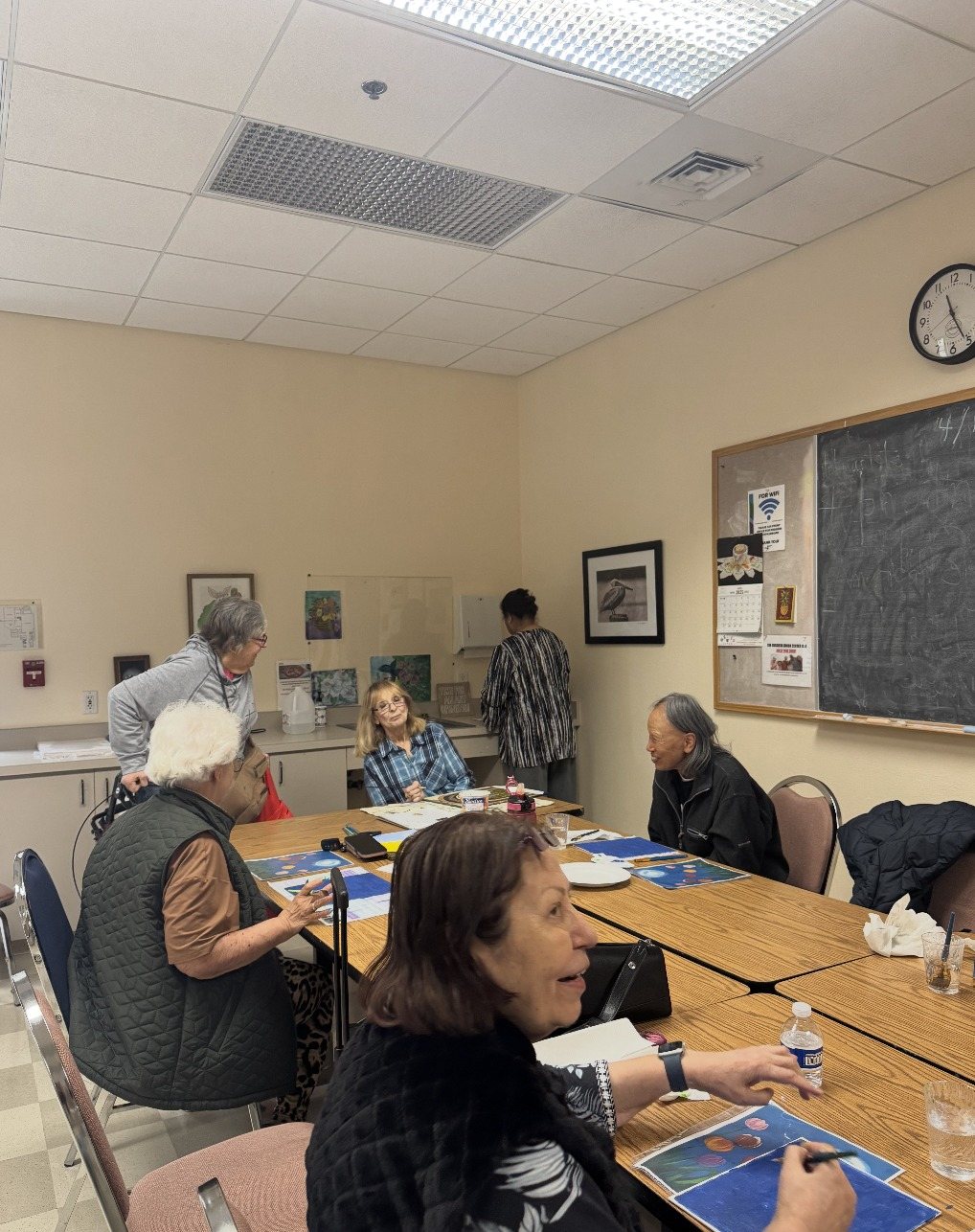 Seniors painting calm blue scenes at a table at Ruggieri Senior Center