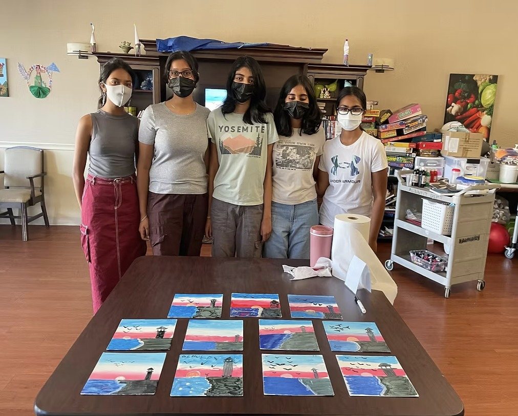 CARES officers standing behind a table of finished sunset paintings